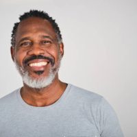 front view portrait of a confident middle aged Dominican man with a grey t-shirt in a white studio background